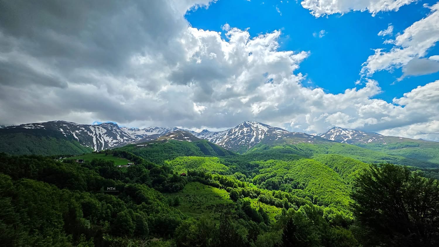 Snow-streaked ridges of the Accursed Mountains above green beech forest in western Kosovo