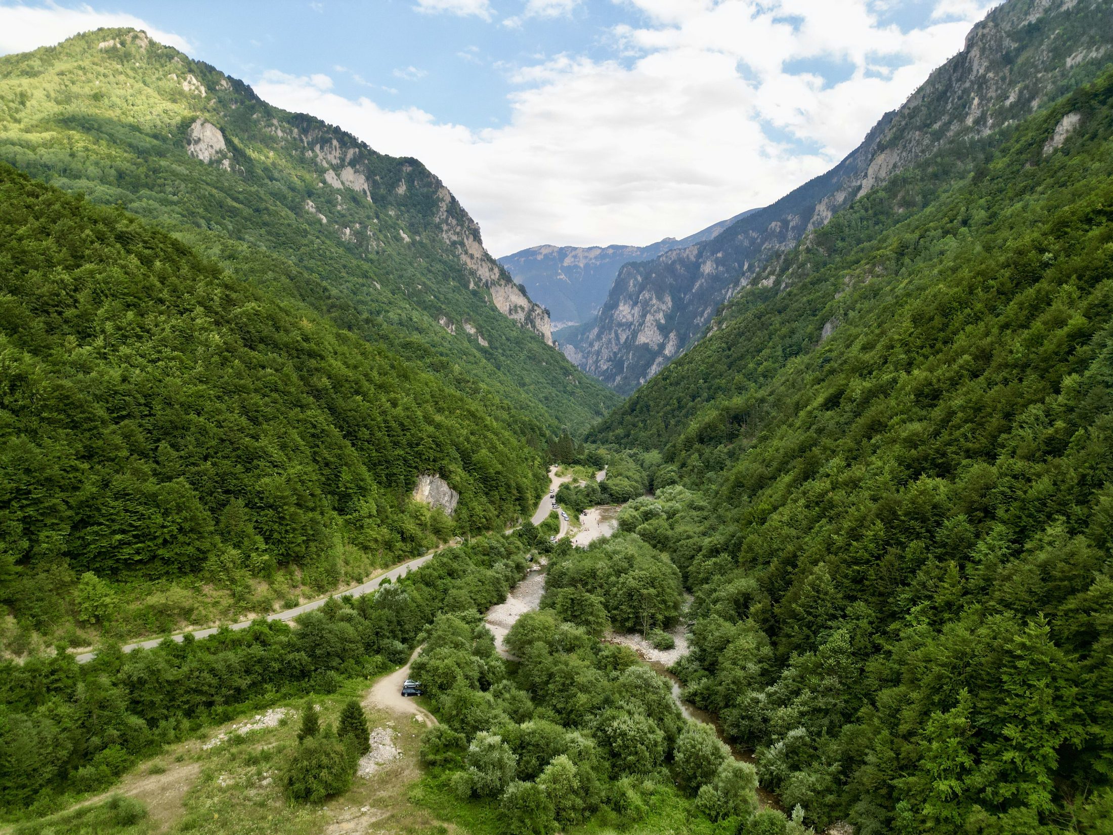 Deep misty Rugova canyon with sheer cliffs and a thin road below